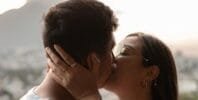 A couple kissing in front of a city view